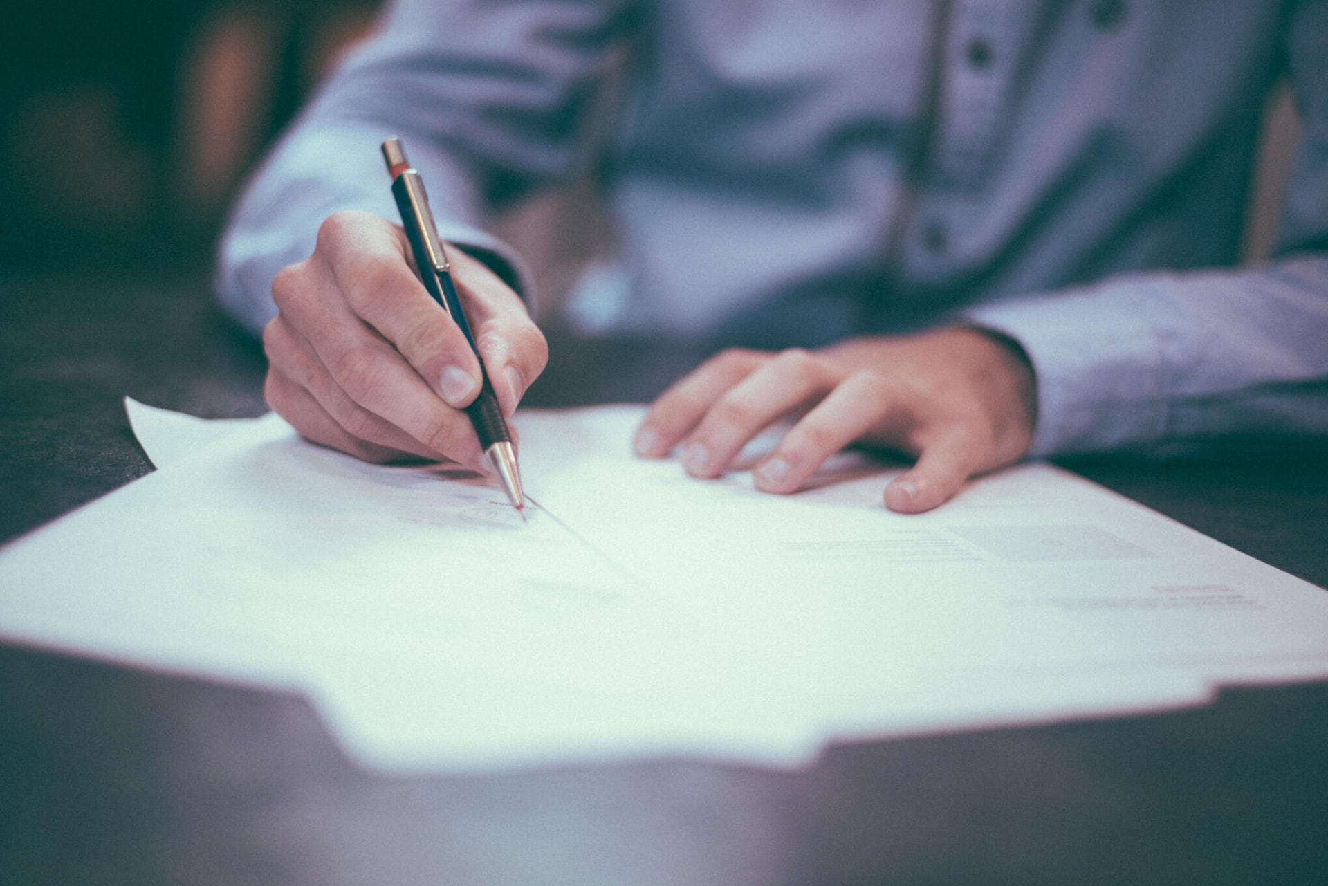 Business owner signing accounting paperwork at a desk